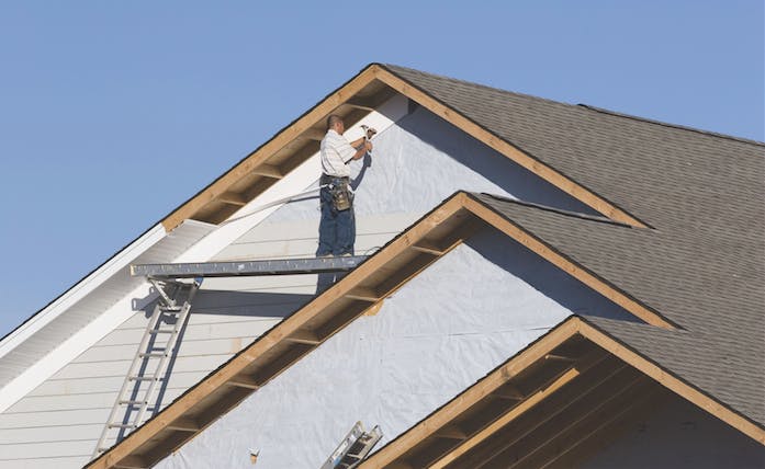 Worker hangs vinyl siding.