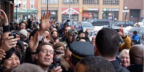 Crowd members scramble for attention from an individual.