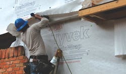 Construction worker installing housewrap on a house Construction worker installing housewrap on a house