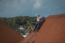 Roofer with harness on rooftop Roofer with harness on rooftop