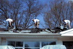 Men on residential roof remove asphalt shingles. Men on residential roof remove asphalt shingles.