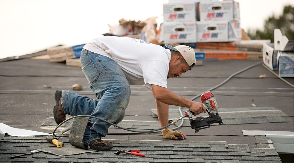Roofer installs asphalt shingles on residential roof