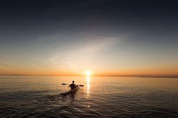 Man paddles off in kayak leaving work behind Man paddles off in kayak leaving work behind