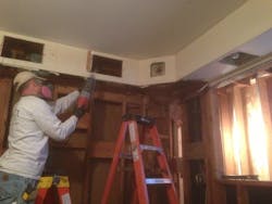 Worker with respirator sawing drywall Worker with respirator sawing drywall