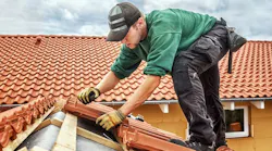 contractor working on a roof for a roofing job with brick