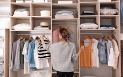 A Woman With Her Back To The Camera, Arranging Clothes In A Large, Well Organized Closet A Woman With Her Back To The Camera, Arranging Clothes In A Large, Well Organized Closet