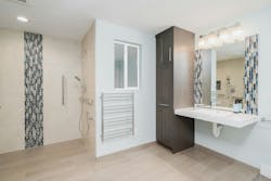 In this remodel, which won Gold in the NAHB’s BALA Awards program, Irons Brothers Construction transformed a rec room and existing powder room into a barrier-free space to accommodate a client who unexpectedly became disabled. The design focused on creating an open, functional layout that accommodated medical equipment and a large power wheelchair. Key features include a ceiling-mounted Hoyer lift, spacious bedroom with multiple layout options, and a fully accessible bathroom with a curb-less shower, floating sink counter, side-mounted faucet, and tall pullout cabinet for easy access to toiletries. The toilet has a washlet feature, which Irons says he installs in about 75% of his projects—for clients young and old, able bodied or otherwise. The suite's entry was designed to allow for future ramp installation, while widened doorways and motion-sensor door openers improve accessibility. In this remodel, which won Gold in the NAHB’s BALA Awards program, Irons Brothers Construction transformed a rec room and existing powder room into a barrier-free space to accommodate a client who unexpectedly became disabled. The design focused on creating an open, functional layout that accommodated medical equipment and a large power wheelchair. Key features include a ceiling-mounted Hoyer lift, spacious bedroom with multiple layout options, and a fully accessible bathroom with a curb-less shower, floating sink counter, side-mounted faucet, and tall pullout cabinet for easy access to toiletries. The toilet has a washlet feature, which Irons says he installs in about 75% of his projects—for clients young and old, able bodied or otherwise. The suite's entry was designed to allow for future ramp installation, while widened doorways and motion-sensor door openers improve accessibility.