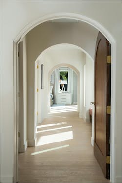 The hallway to the primary suite (above) features the same arch details used throughout the house and leads the eye to a new window looking out to the backyard. The primary bedroom (below) had an unloved gas fireplace that was removed during the remodel, allowing the bed to be centered on the back wall. New sliding doors open to the pool. Wood beams add interest and are a cohesive design element—they’re also used in the family room and the kitchen. The hallway to the primary suite (above) features the same arch details used throughout the house and leads the eye to a new window looking out to the backyard. The primary bedroom (below) had an unloved gas fireplace that was removed during the remodel, allowing the bed to be centered on the back wall. New sliding doors open to the pool. Wood beams add interest and are a cohesive design element—they’re also used in the family room and the kitchen.