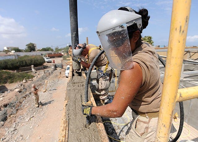 US Navy Builder Constructionmen Diana Aceves, right, and Daniel Fuentes vibrate concrete as part of a Naval Mobile Construction Battalion.