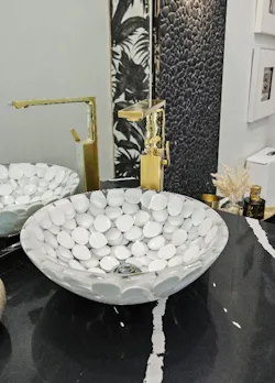 A handmade Italian vessel sink, inlaid with polished river pebbles, contributes to the stone aesthetic and helps “bring organic texture and artisanal craftsmanship into the room.”