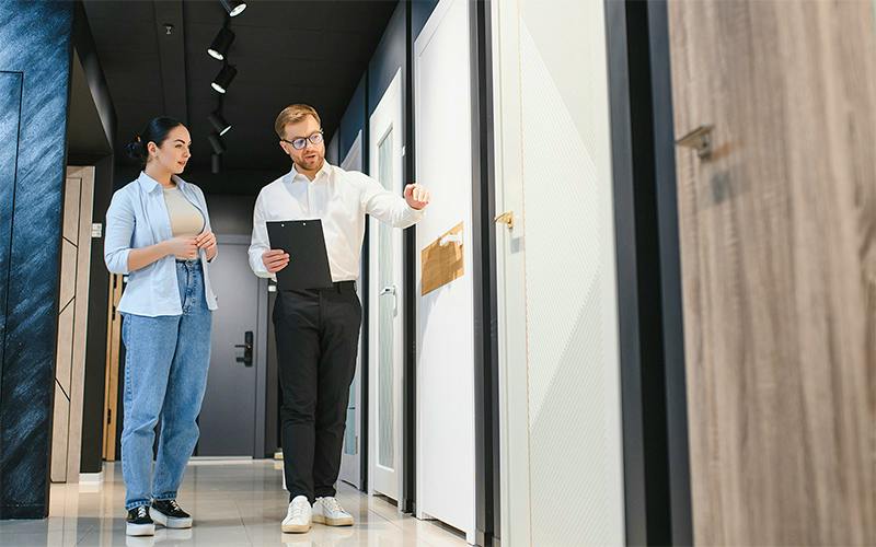 Two people discuss door and finish options in a home design showroom.
