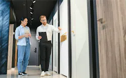 Two people discuss door and finish options in a home design showroom.